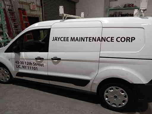 A white van with jaycee maintenance corp written on the side is parked in a garage.