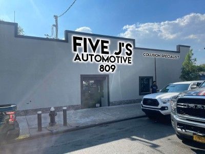 A group of cars are parked in front of a building that says five j 's automotive 809.