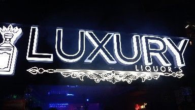 A neon sign for luxury liquor is lit up at night.