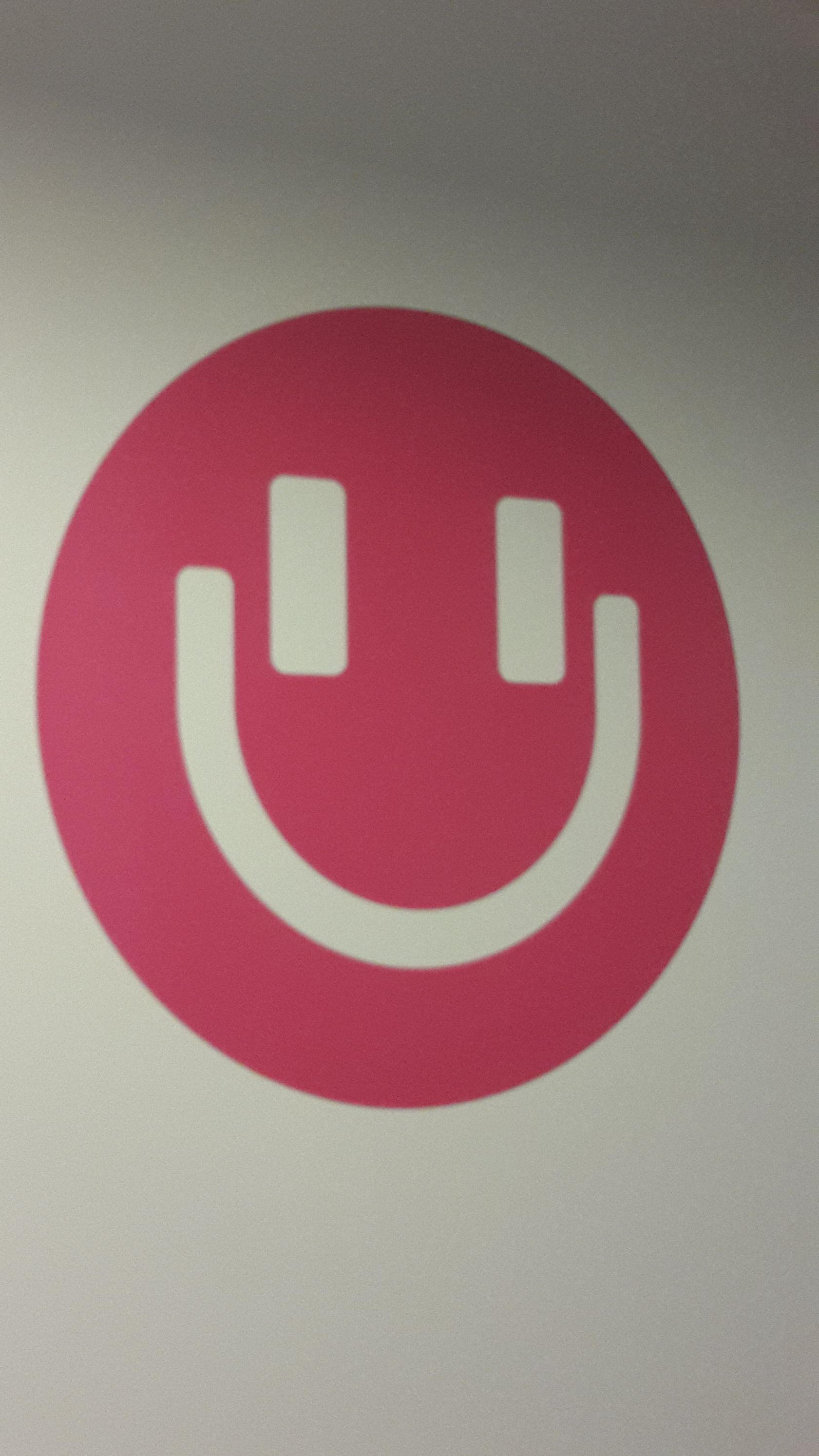A pink circle with a white smiley face inside of it.