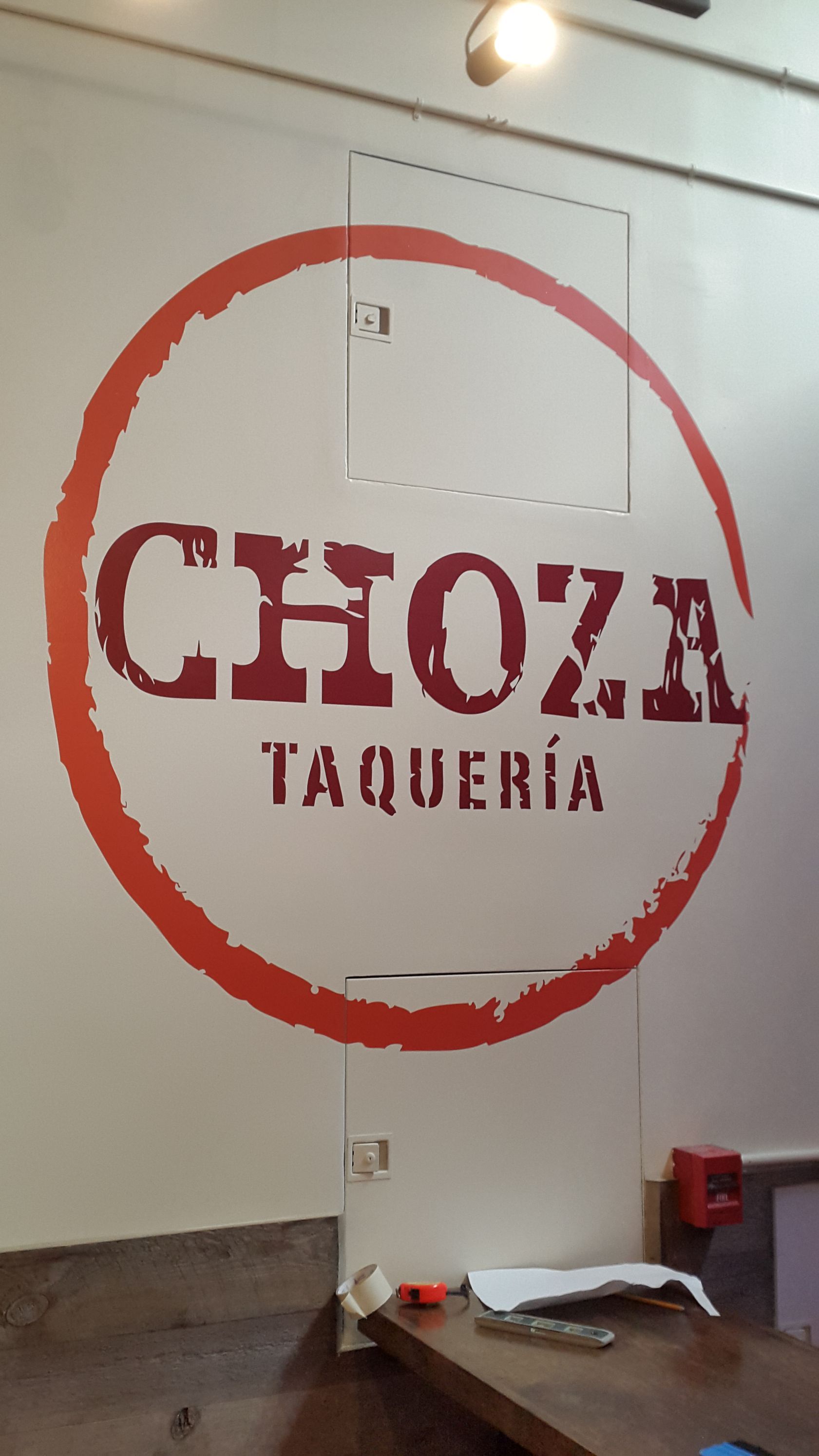 A white wall with a red circle that says choza taqueria