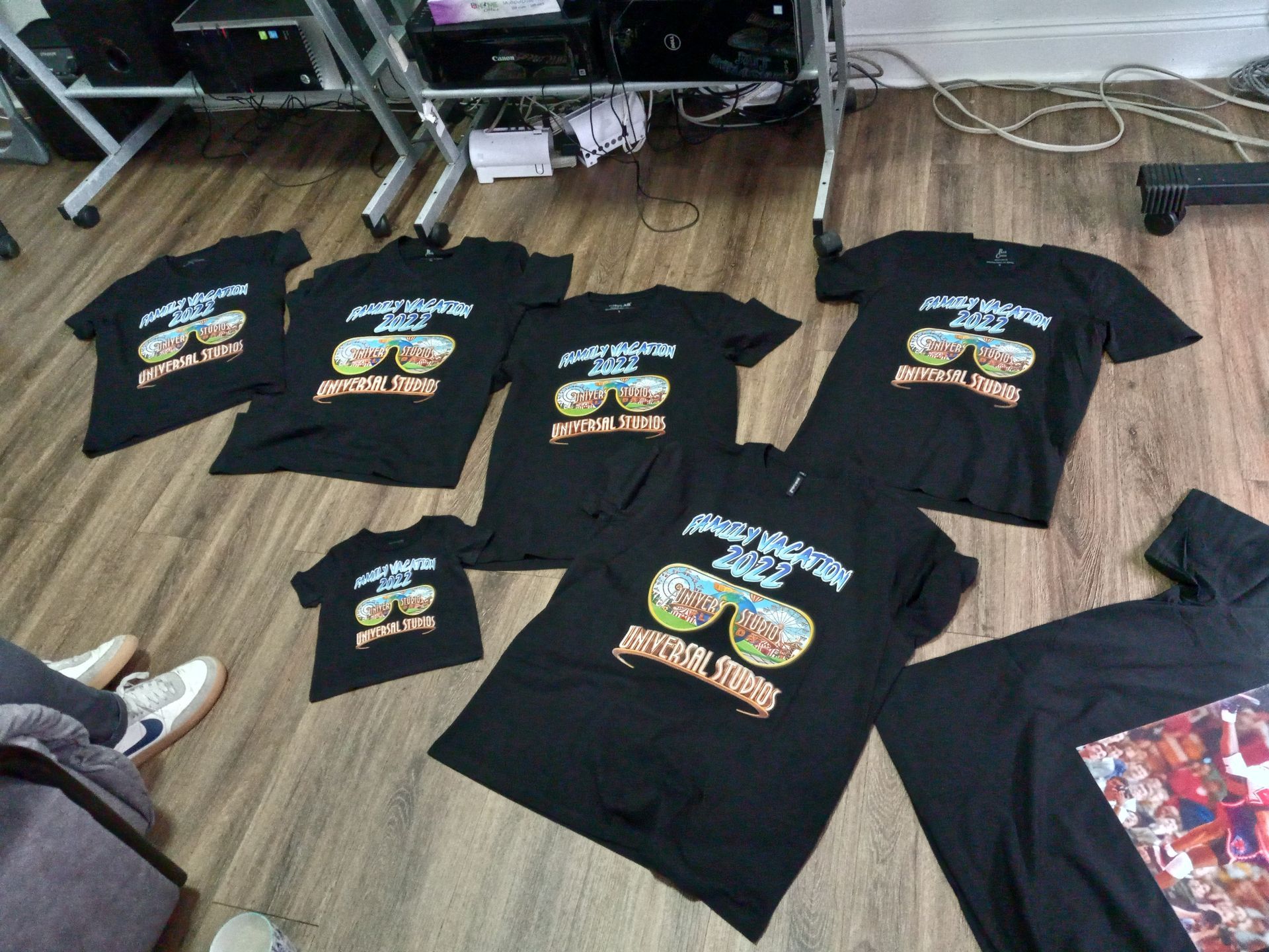A bunch of black t-shirts are laying on the floor