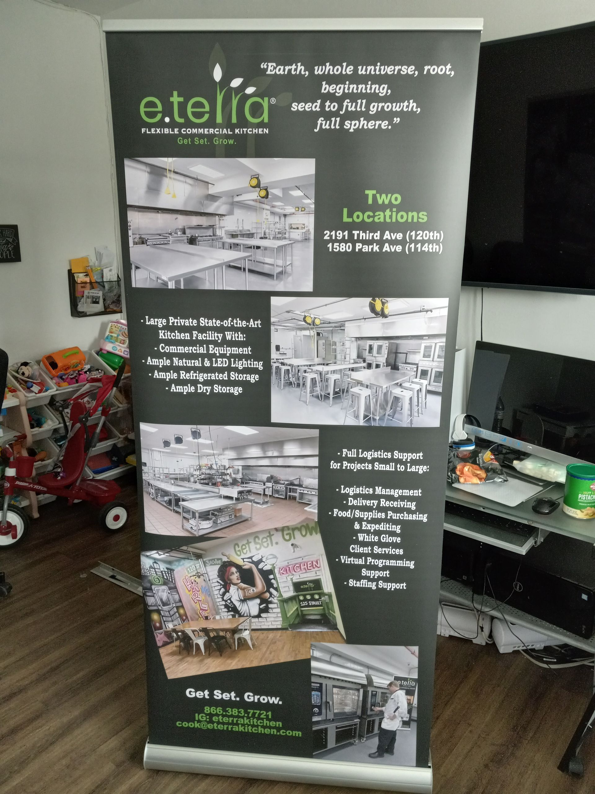 A roll up banner is sitting on a wooden floor in a living room.