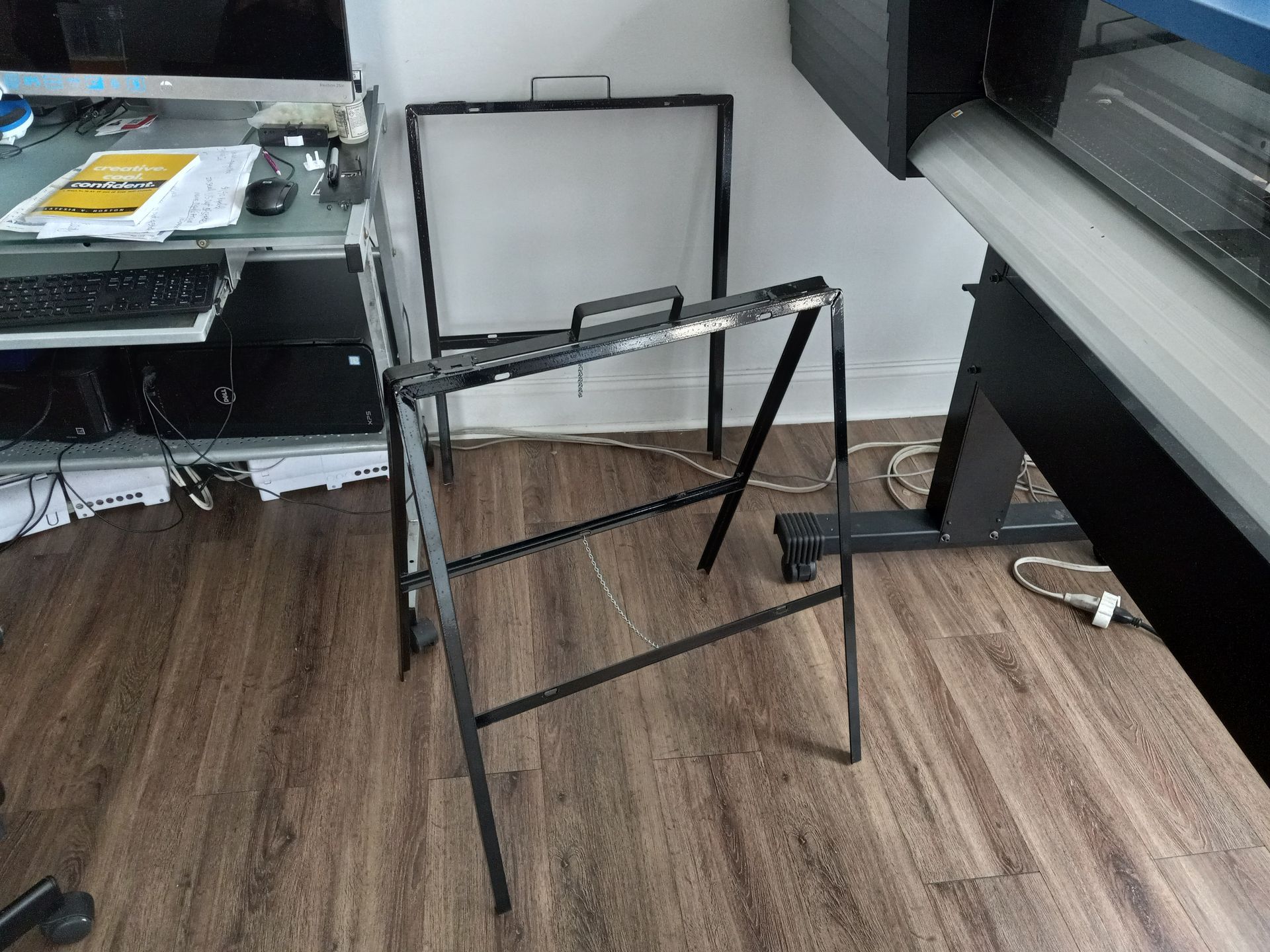 A metal frame is sitting on a wooden floor next to a computer desk.