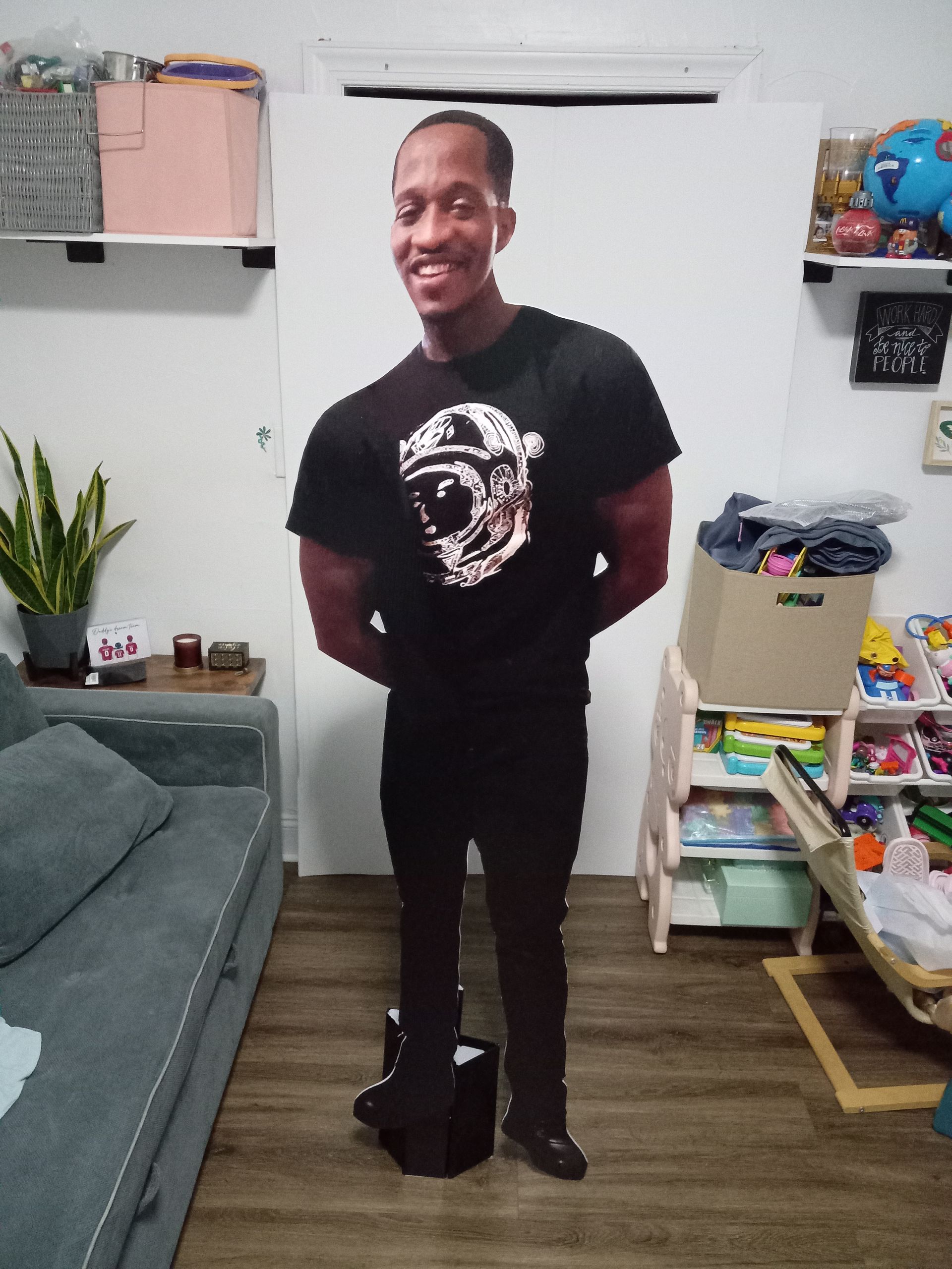 A man in a black shirt is standing in a living room.