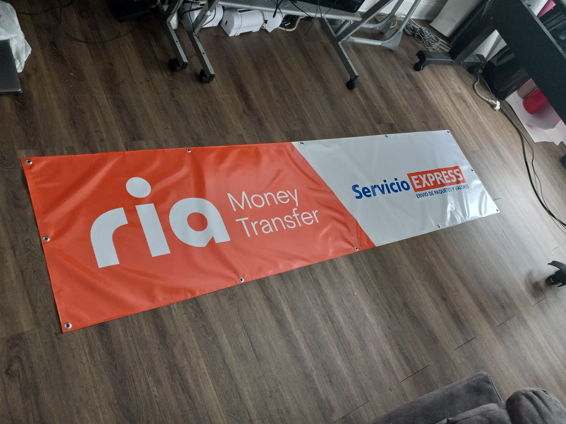 A banner for ria money transfer is sitting on a wooden floor.