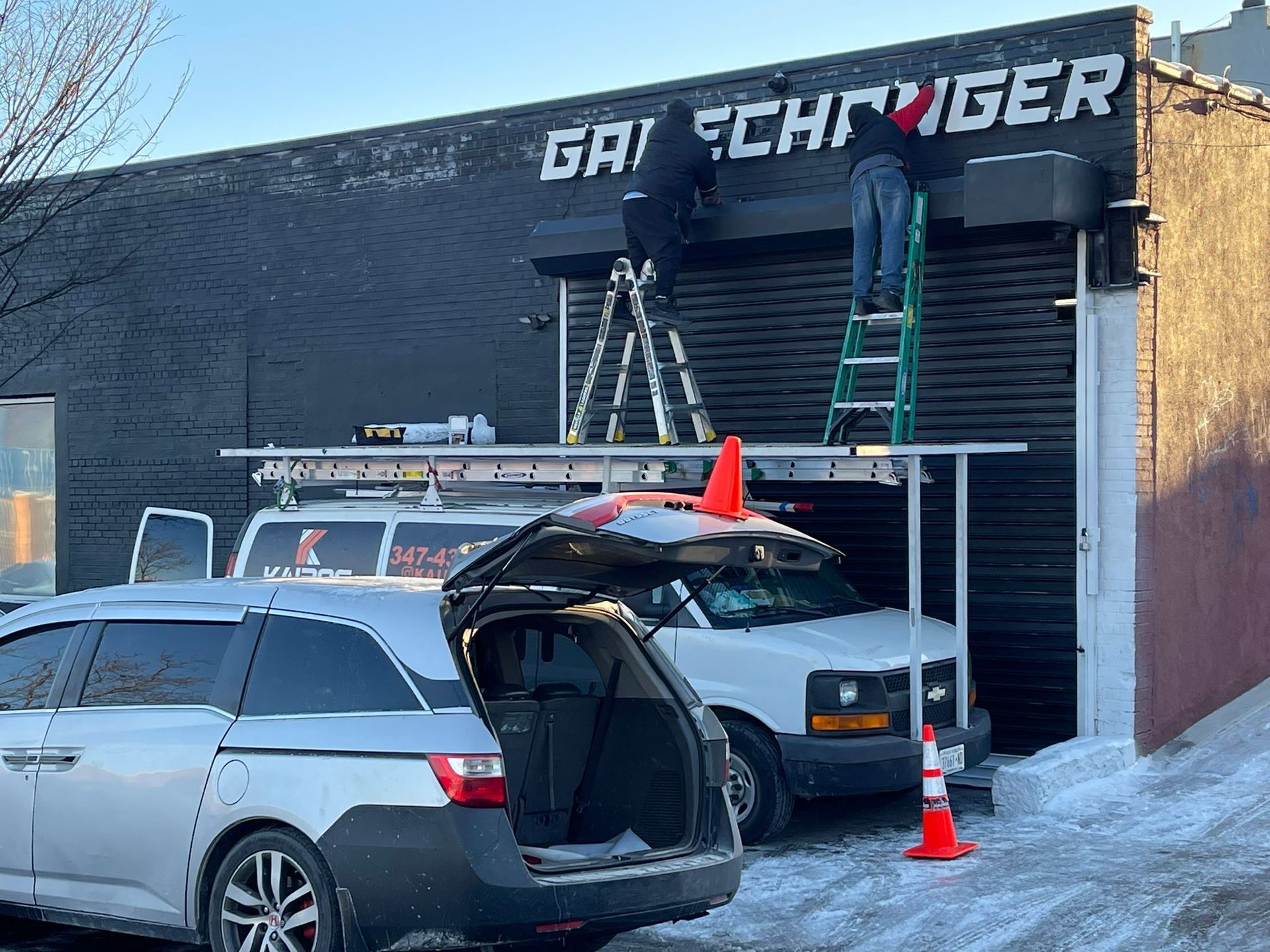 A man on a ladder is working on a garage door.