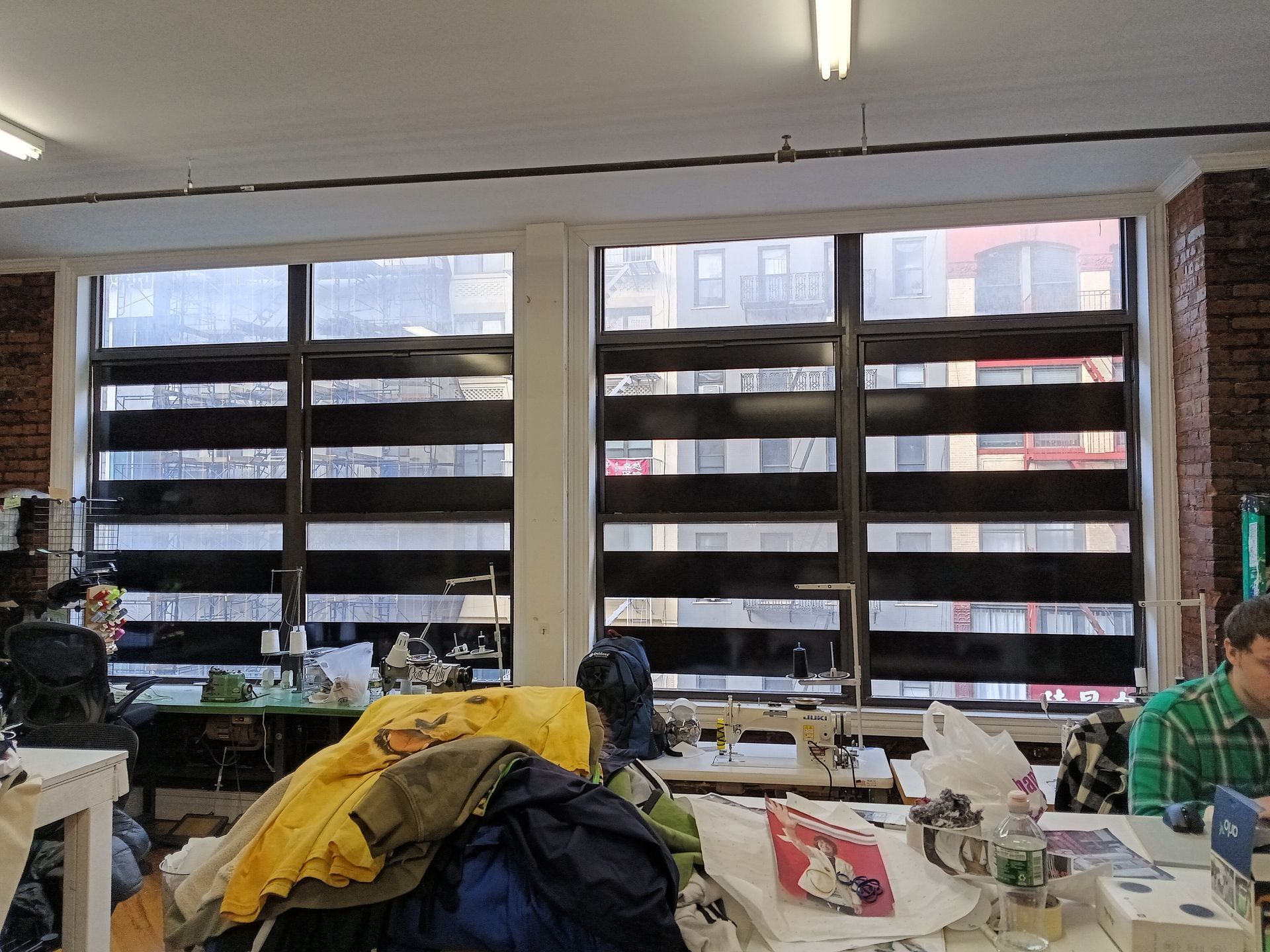 A man sits at a desk in front of a large window