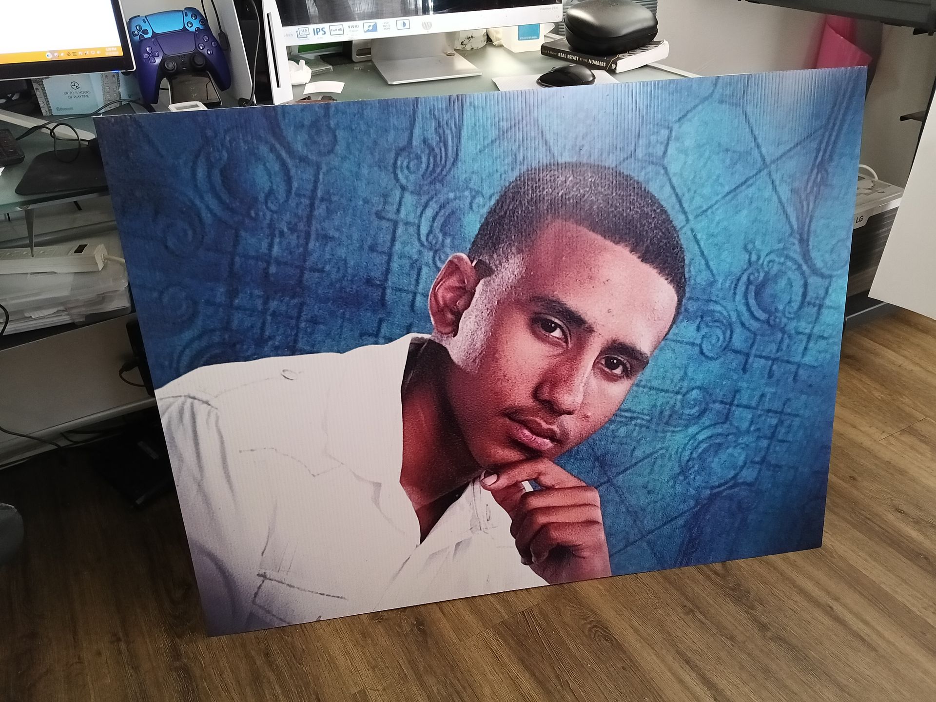A painting of a man with his hand on his chin is sitting on a wooden floor.