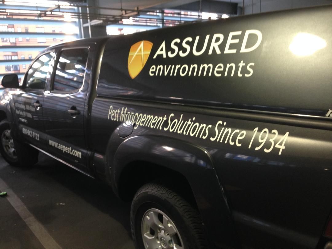 An assured environments truck is parked in a parking garage