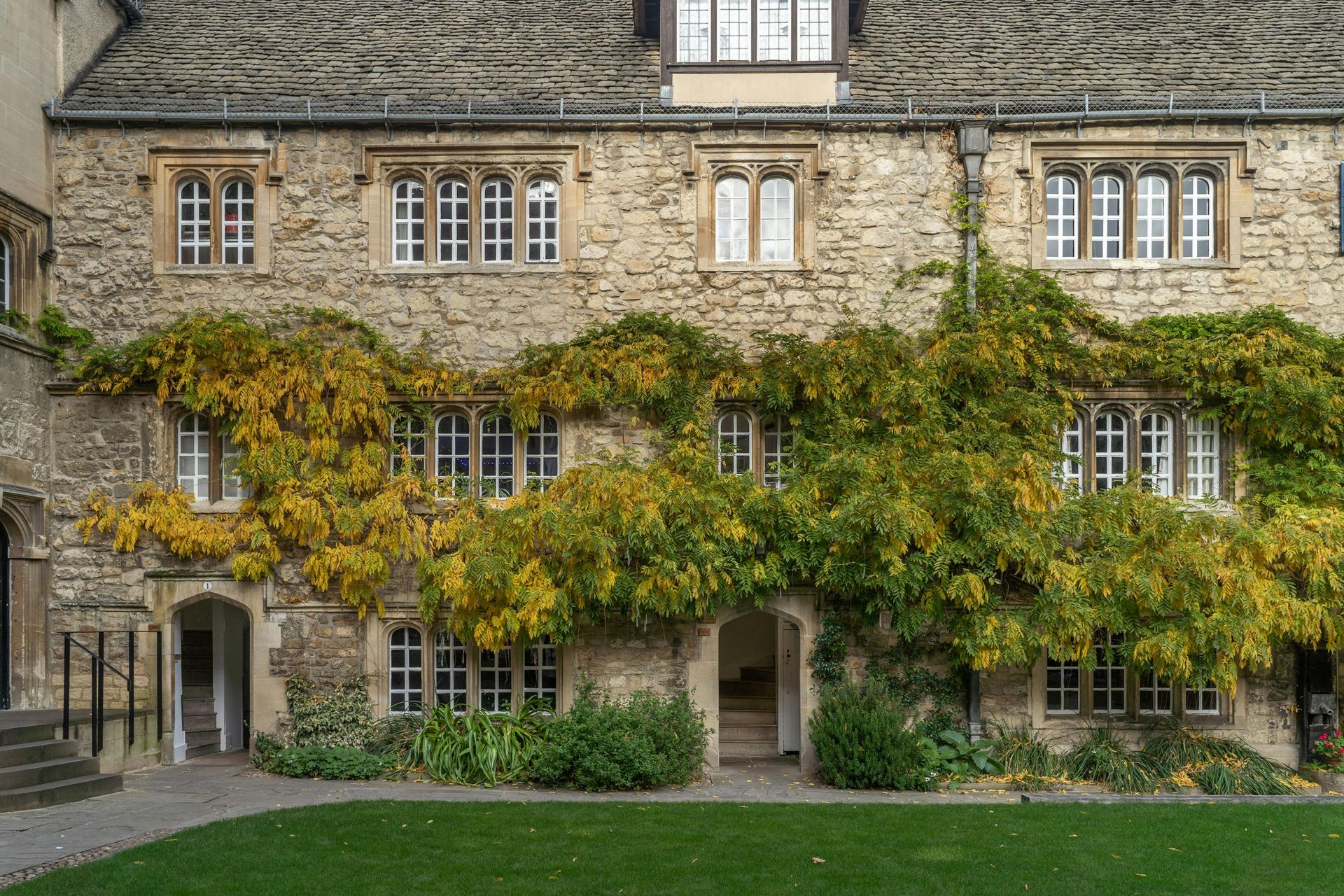 A large stone building with lots of windows and ivy growing on it