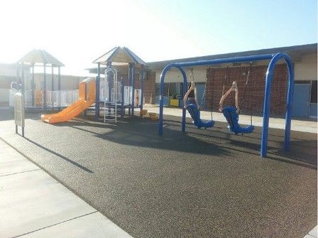 A playground with a slide and swings in front of a building
