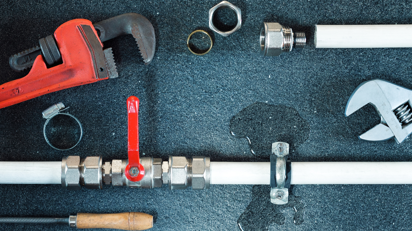 A bunch of plumbing tools are laying on a black surface.