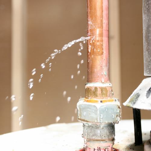 A close up of a copper pipe with water coming out of it.