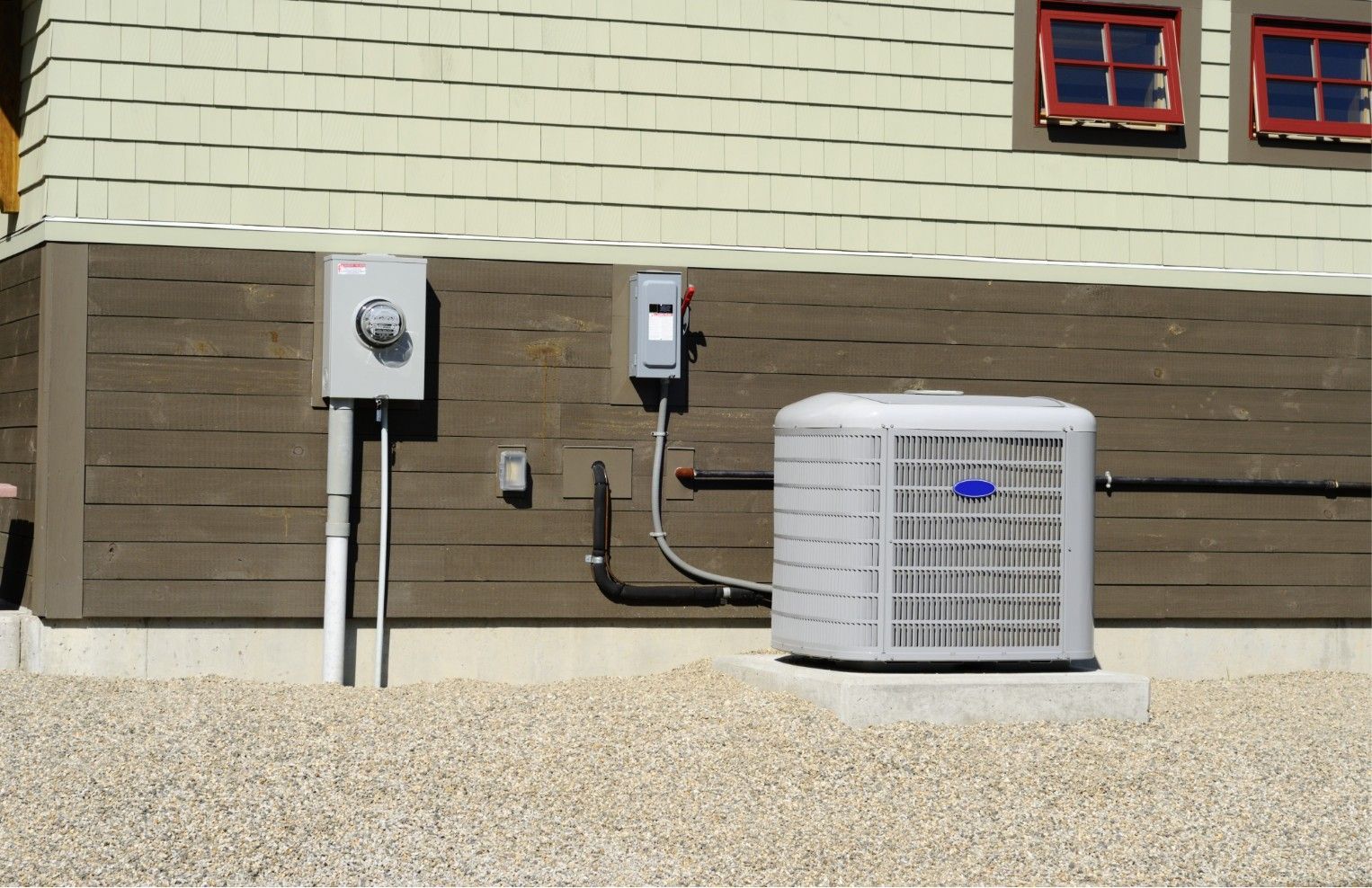 Outdoor HVAC unit, electrical boxes, and conduit mounted on a house exterior wall.