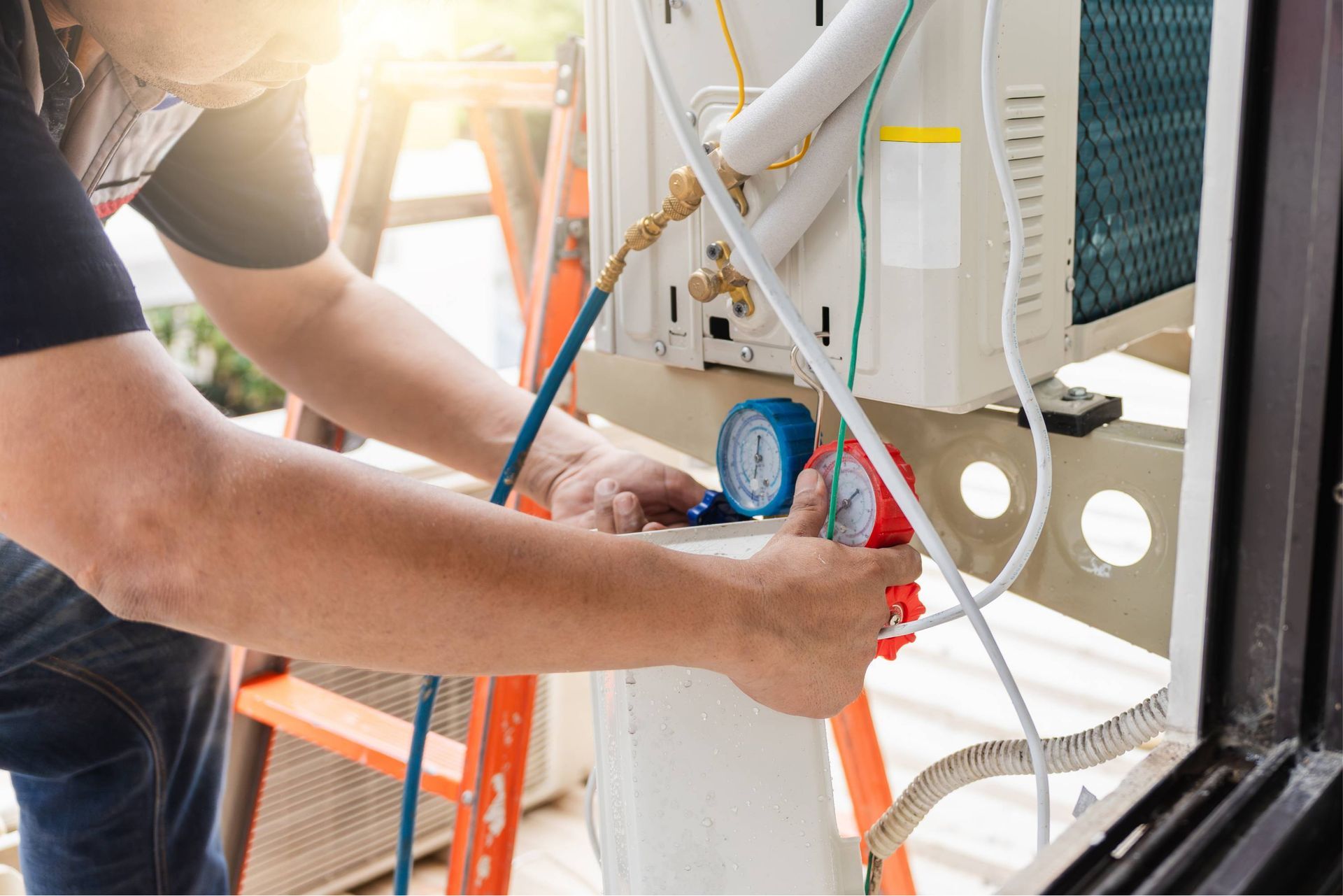 Technician checking HVAC unit with gauges and hoses outdoors