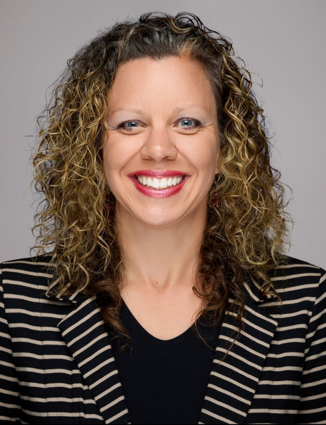 A woman is sitting at a desk with a laptop and a vase of flowers.