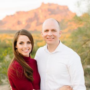 A man and a woman are posing for a picture in front of a mountain.