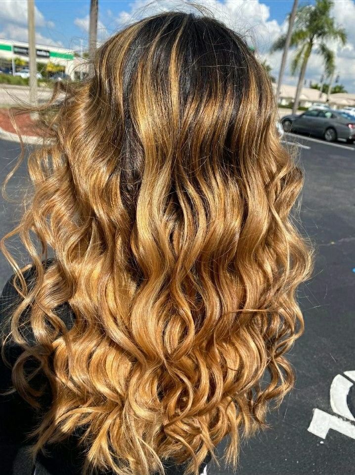 A woman is holding a stack of hair color samples in front of her hair.