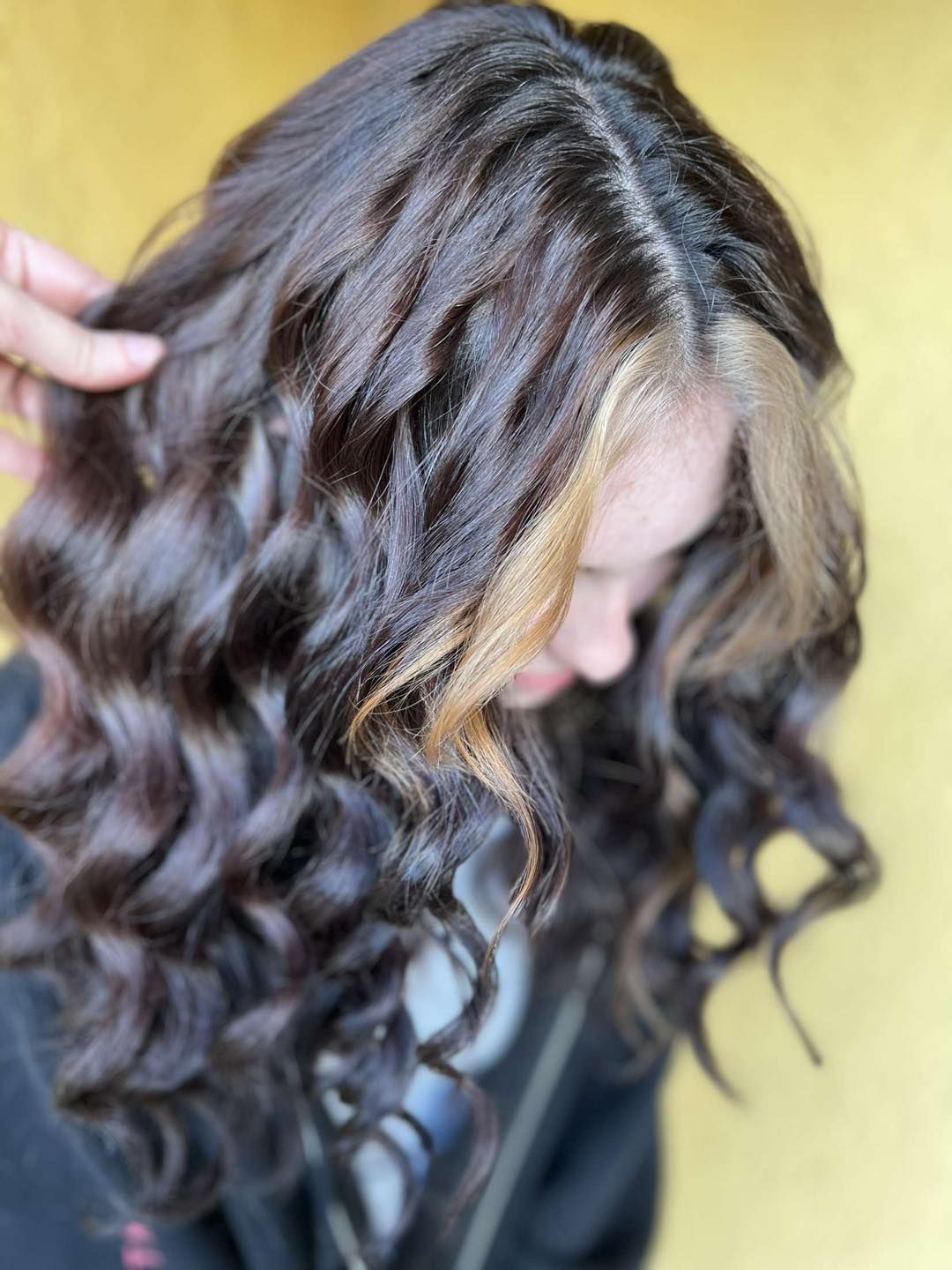 A woman with purple and blue hair is getting her hair dyed by a hairdresser.