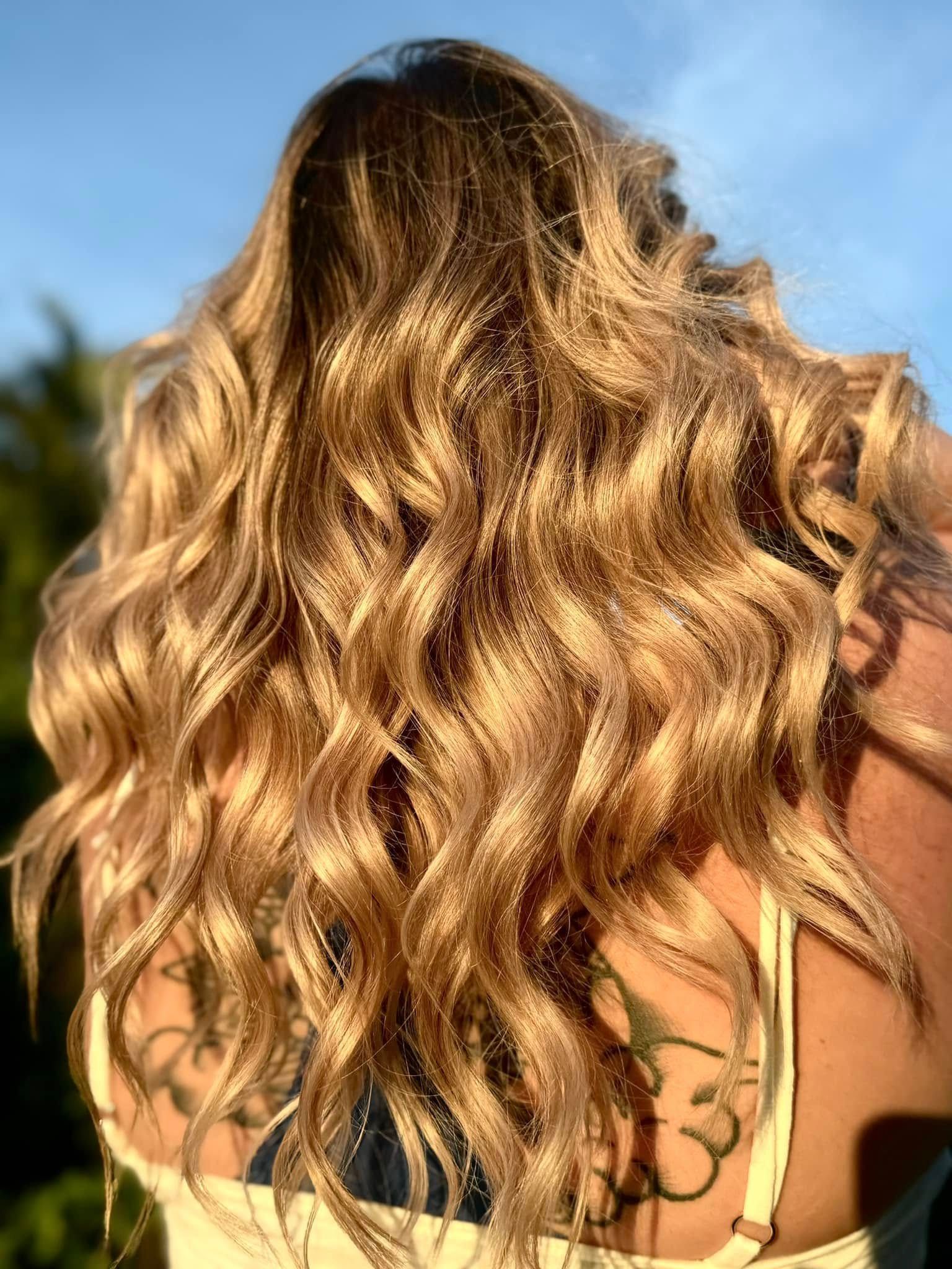 A woman is getting her hair done by a hairdresser in a salon.