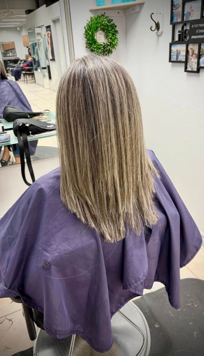 A woman is getting her hair cut by a hairdresser.