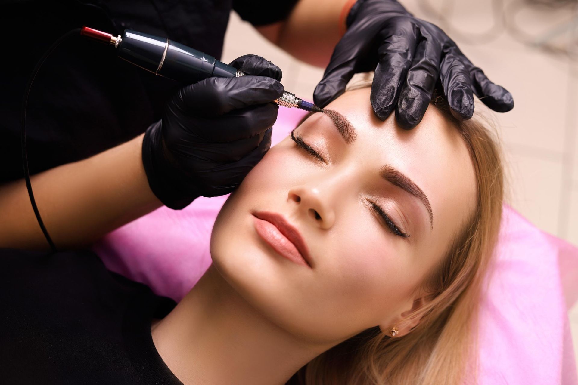 A woman is getting permanent makeup on her eyebrows.