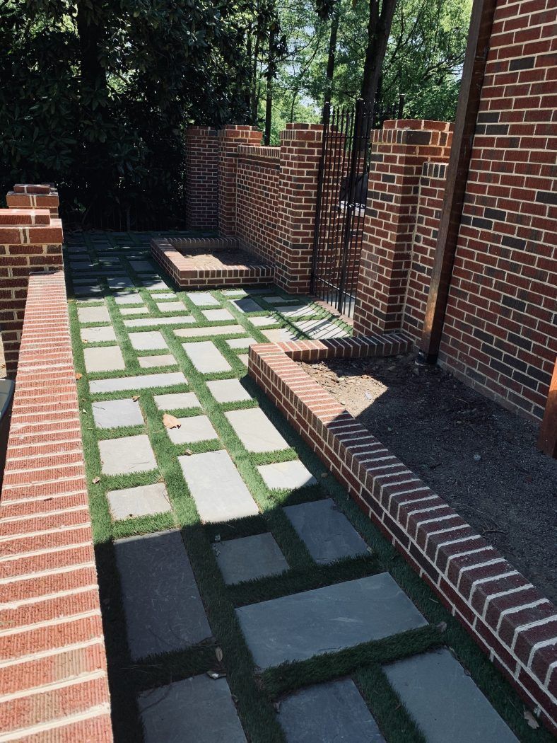 A brick walkway with grass and brick walls