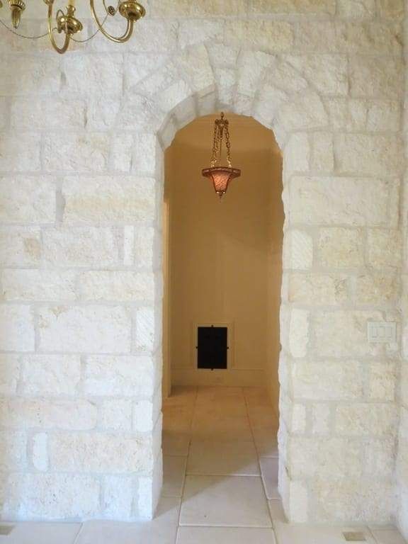 A stone archway leading to a room with a chandelier hanging from the ceiling