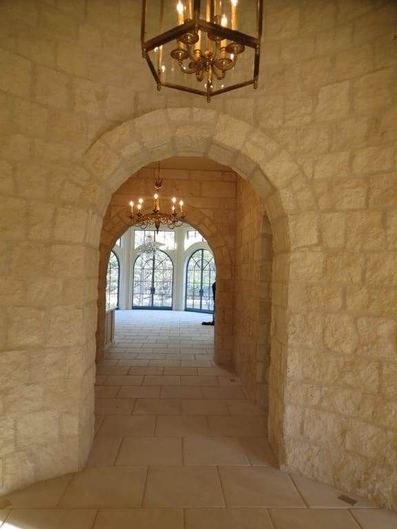 A hallway with arches and a chandelier hanging from the ceiling