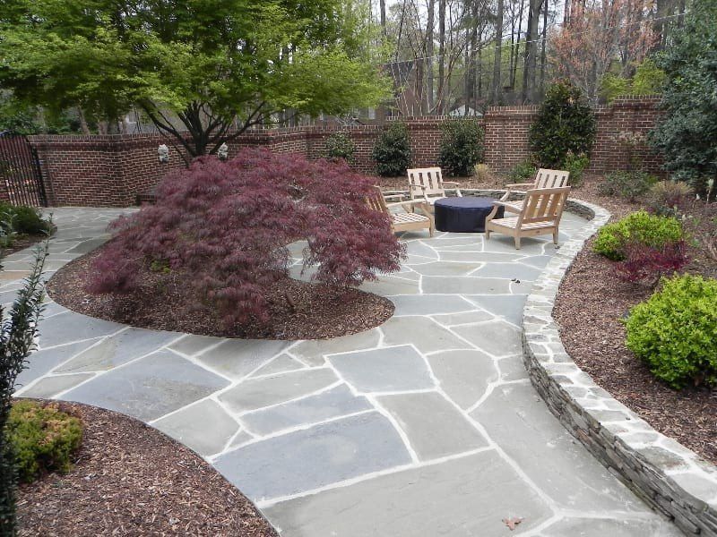 A stone patio with chairs and a fire pit