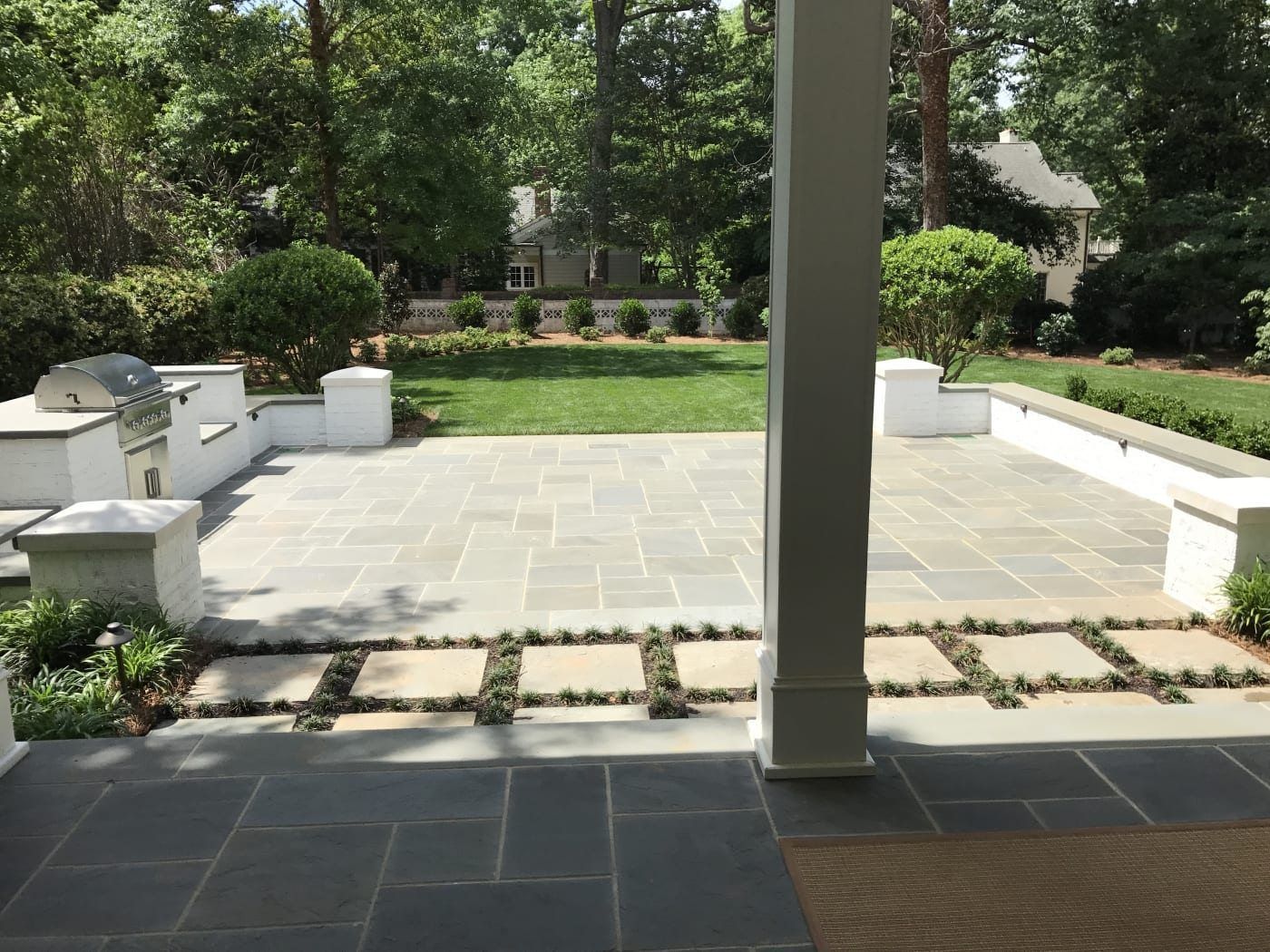 A patio with a grill and a lawn in the background