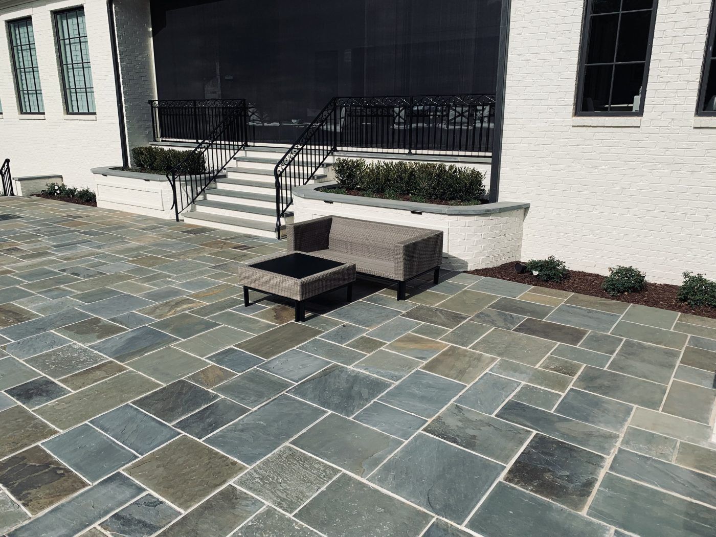 A patio with a chair and ottoman in front of a house