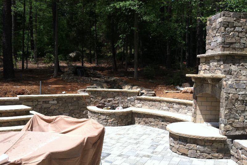 A patio with a fireplace and a table with a cover on it