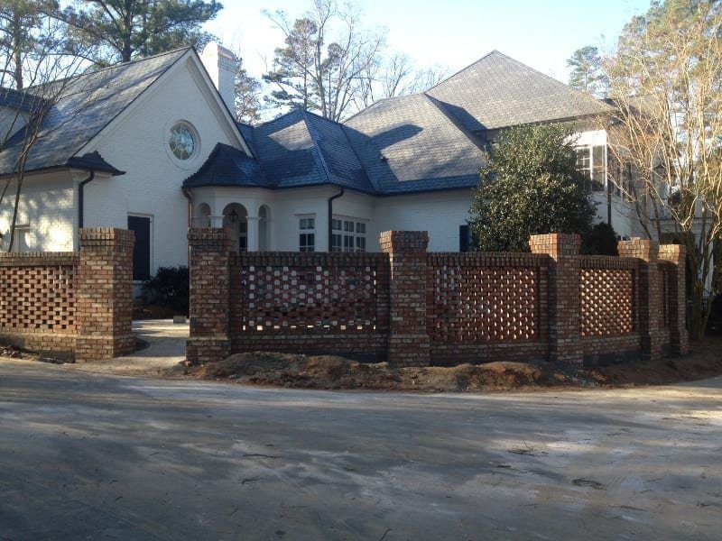 A large white house with a brick fence in front of it