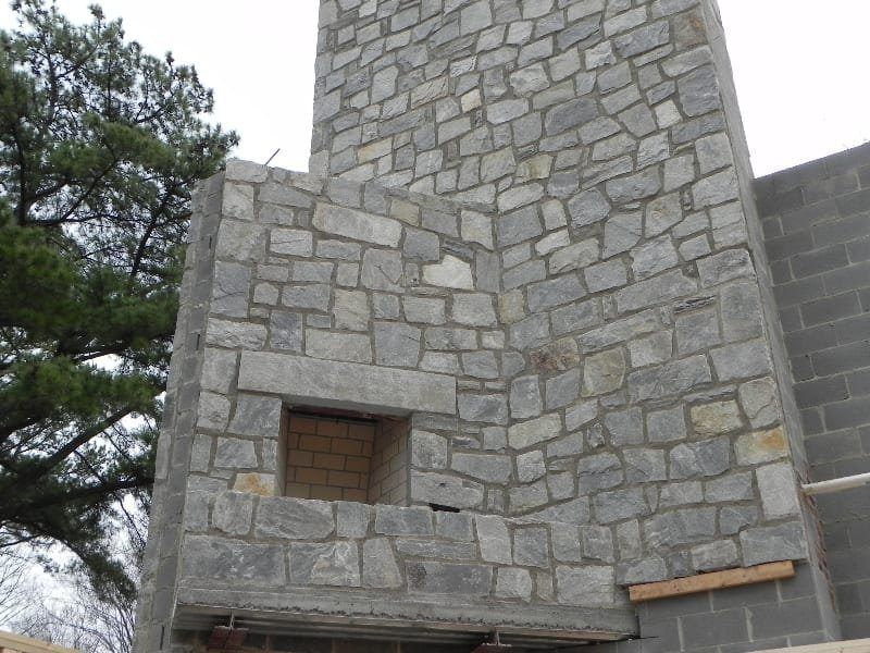 A stone wall with a window in the middle of it