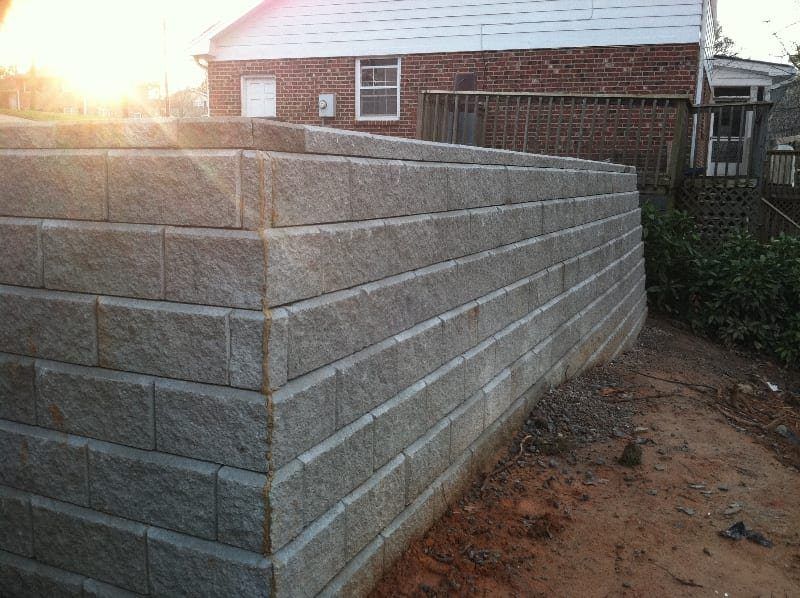 A brick wall is being built in front of a brick house