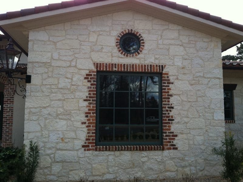A stone building with a brick trim around a window