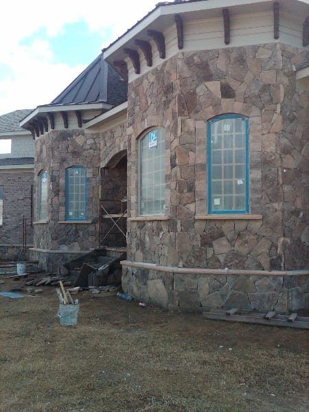 A stone building with blue windows is being built