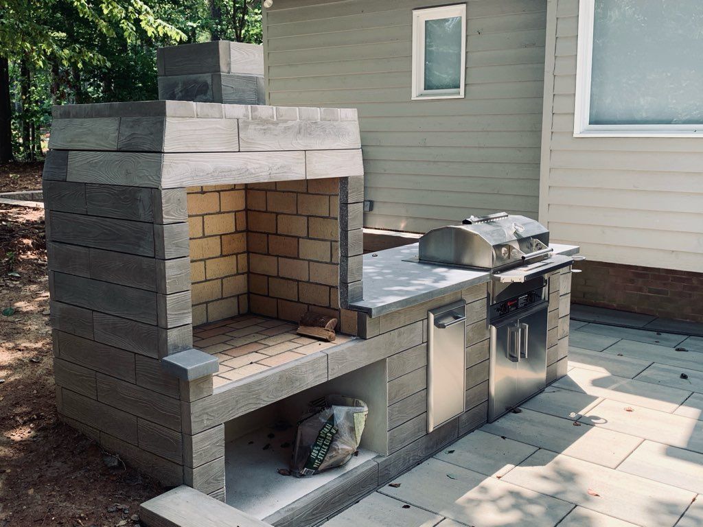 A brick fireplace is being built in the backyard of a house.