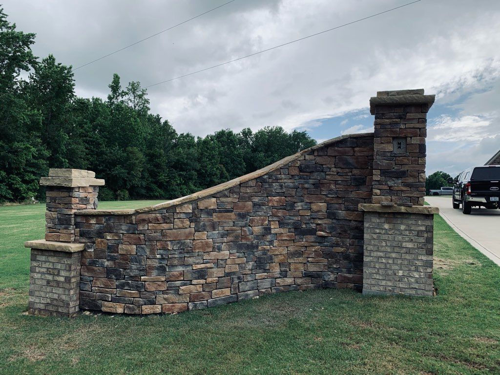 A stone wall with pillars and a truck parked in front of it