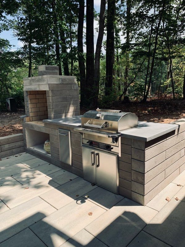 An outdoor kitchen with a grill and a fireplace
