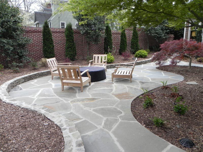 A stone patio with chairs and a table in the middle