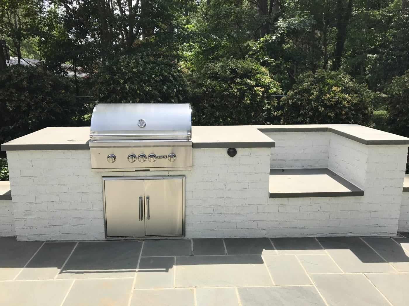 A grill is built into a white brick wall