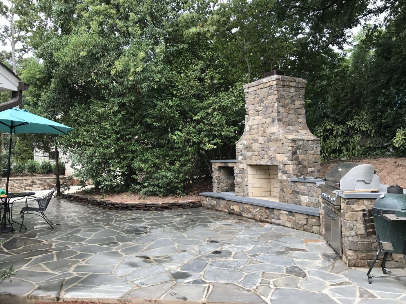 A patio with a fireplace, grill and umbrellas