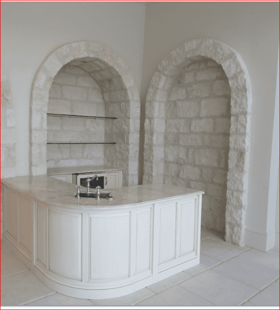 A kitchen with white cabinets and brick arches