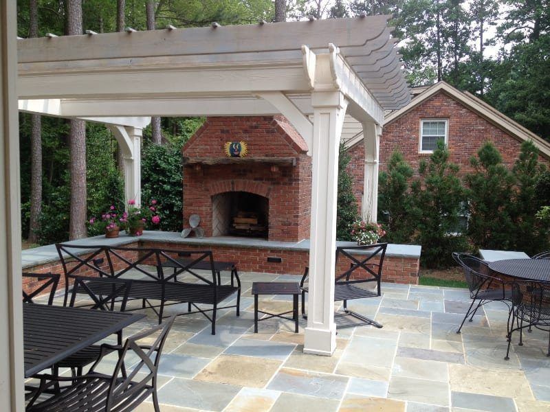 A patio with a fireplace and tables and chairs under a pergola