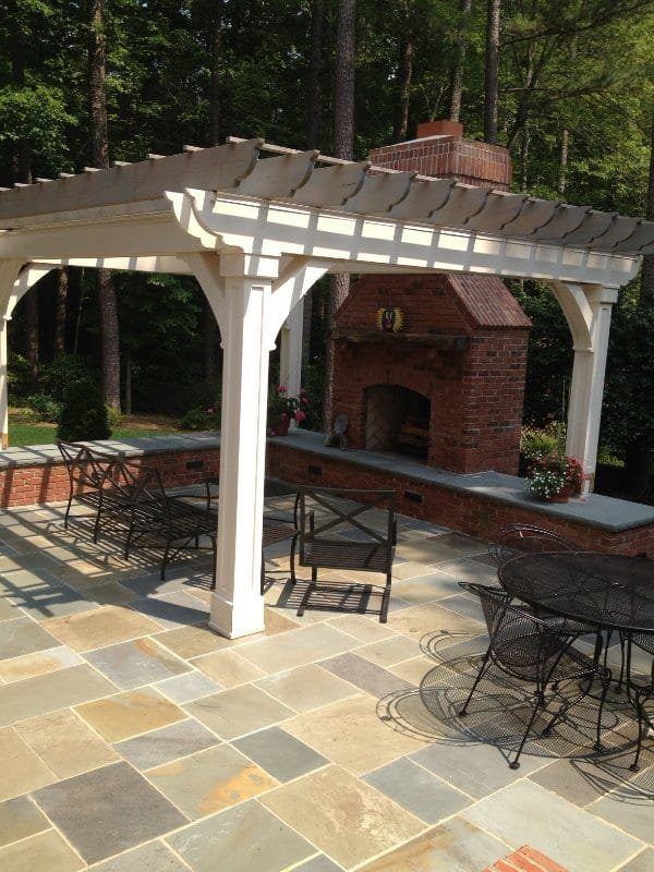 A patio with a pergola and a fireplace