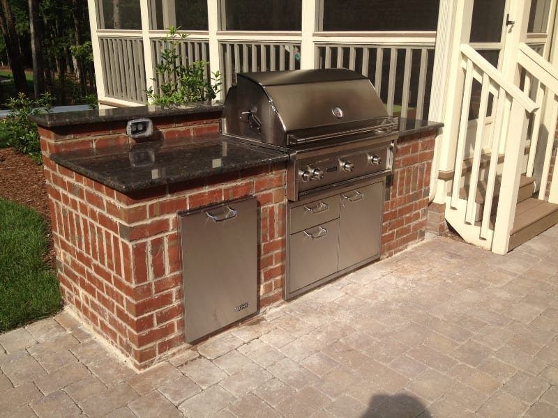 A grill is built into a brick wall on a patio
