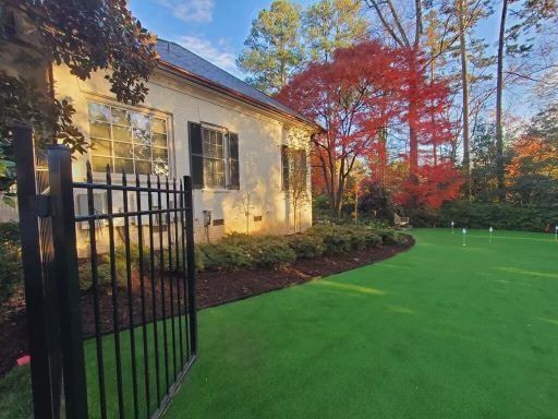 A white house with a black fence and a green lawn in front of it